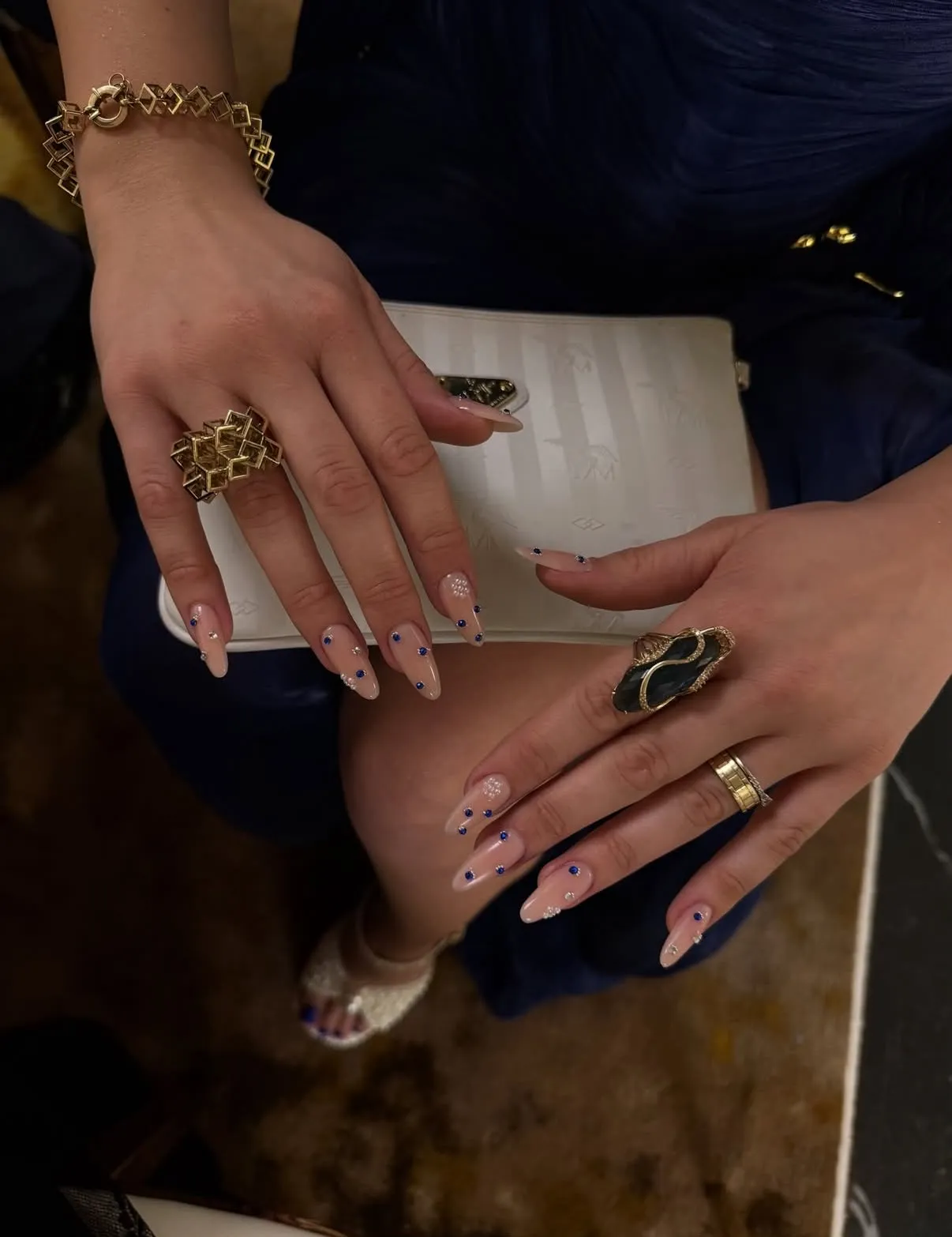 Mandelförmige nude Nägel mit blauen Punkten und Strass